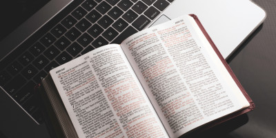 Open Bible sitting on Laptop keyboard