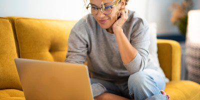 Woman working on her laptop while on her sofa couch