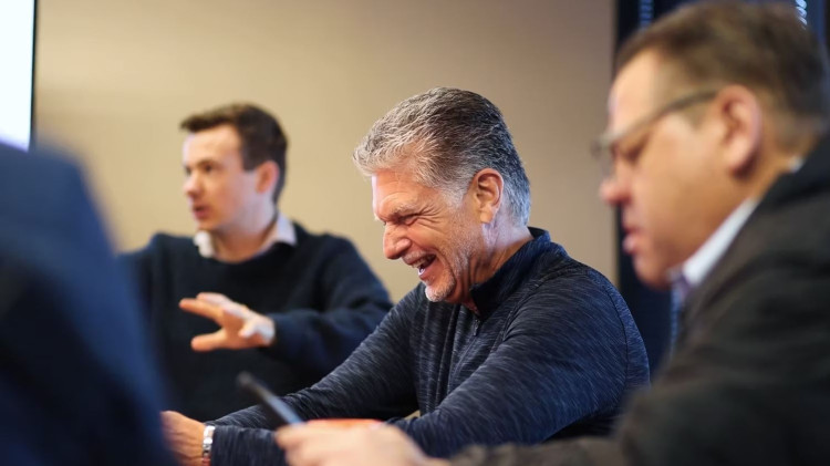 Bob laughing in a meeting among peers