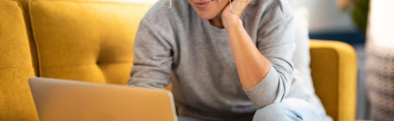 Woman working on her laptop while on her sofa couch